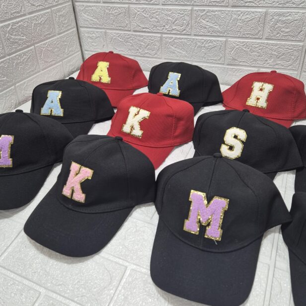 Personalized letter initial cap with glittery monogram, available in multiple colors including red, black, and white. No color choice for the monogram.