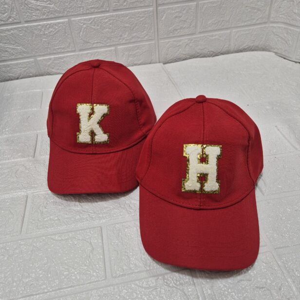 Personalized letter initial cap with glittery monogram, available in multiple colors including red, black, and white. No color choice for the monogram.