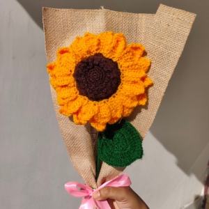 Handmade crochet sunflower bouquet wrapped in brown fabric with a pink ribbon.