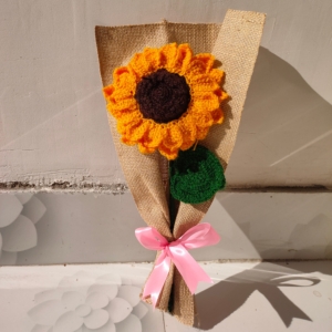 Handmade crochet sunflower bouquet wrapped in brown fabric with a pink ribbon.