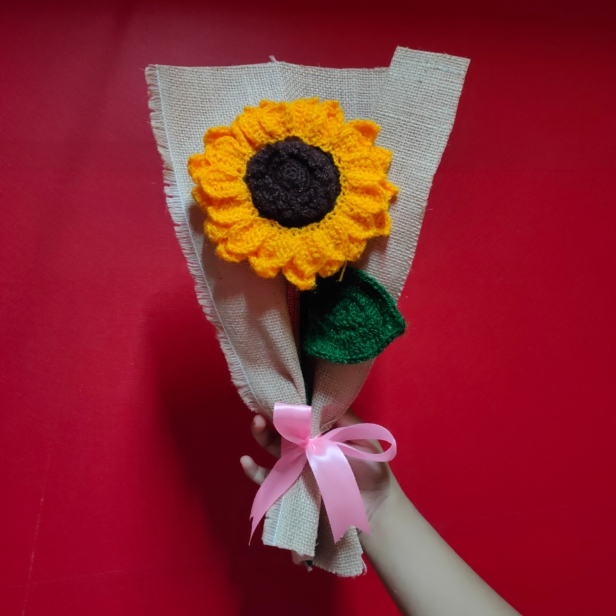 Handmade crochet sunflower bouquet wrapped in brown fabric with a pink ribbon.