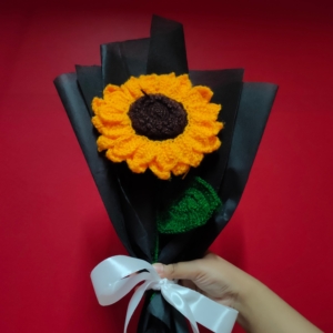Handmade crochet sunflower bouquet wrapped in brown fabric with a pink ribbon.