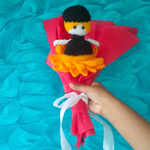 A handmade crochet sunflower that transforms into a doll, wrapped in red wrapping paper.