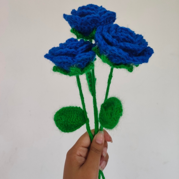 Customizable blue crochet rose bouquet with white wrapping and pink ribbon.