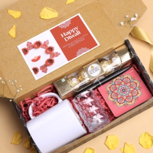 Diwali gift box with Ferrero Rocher chocolates, white ceramic mug, candle holder, and festive rangoli card.
