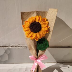 Handmade crochet sunflower bouquet wrapped in brown fabric with a pink ribbon.