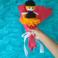 A handmade crochet sunflower that transforms into a doll, wrapped in red wrapping paper.